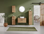 Runder Spiegel an einer grünen Wand in einem stilvollen Badezimmer mit Holzschränken und moderner Einrichtung, Frontalansicht.