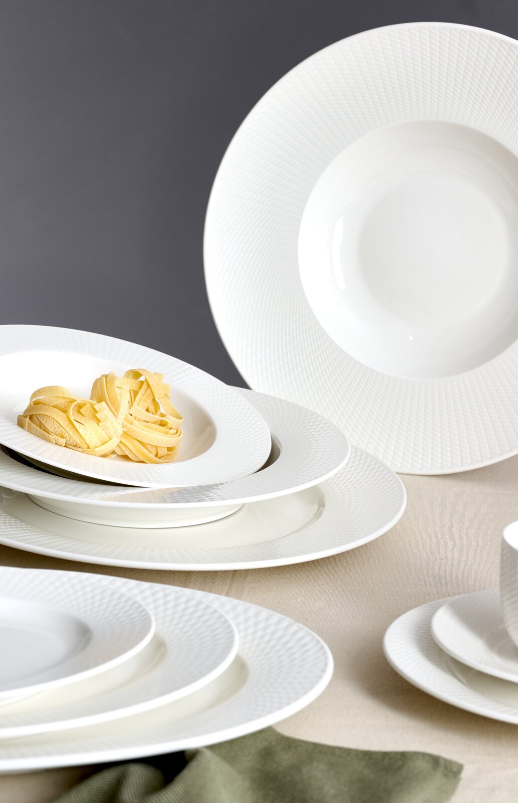 Elegantes weißes Kaffeeset mit feiner Struktur, bestehend aus Tellern und Tassen, aus seitlicher Perspektive fotografiert.
