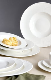 Elegante witte koffieset met een fijne structuur, bestaande uit borden en kopjes, gefotografeerd vanuit een zijaanzicht.