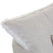 Nahaufnahme eines Sessels mit weichem, hellbeigem Stoffbezug und flauschigem Rand, seitliche Perspektive.