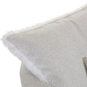 Nahaufnahme eines Sessels mit weichem, hellbeigem Stoffbezug und flauschigem Rand, seitliche Perspektive.