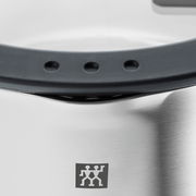 Nahaufnahme eines Edelstahltopfes mit schwarzem Griff und Logo, Perspektive von oben.