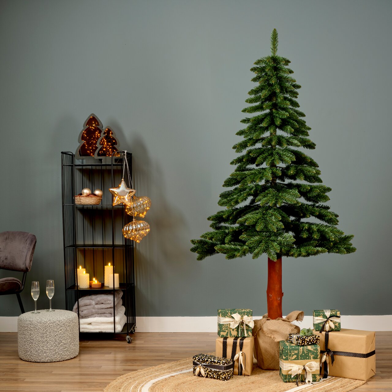 Künstlicher Weihnachtsbaum Tora Kiefer, 180 cm hoch, in einem gemütlich dekorierten Raum mit Geschenken und Lichtern, seitliche Perspektive.