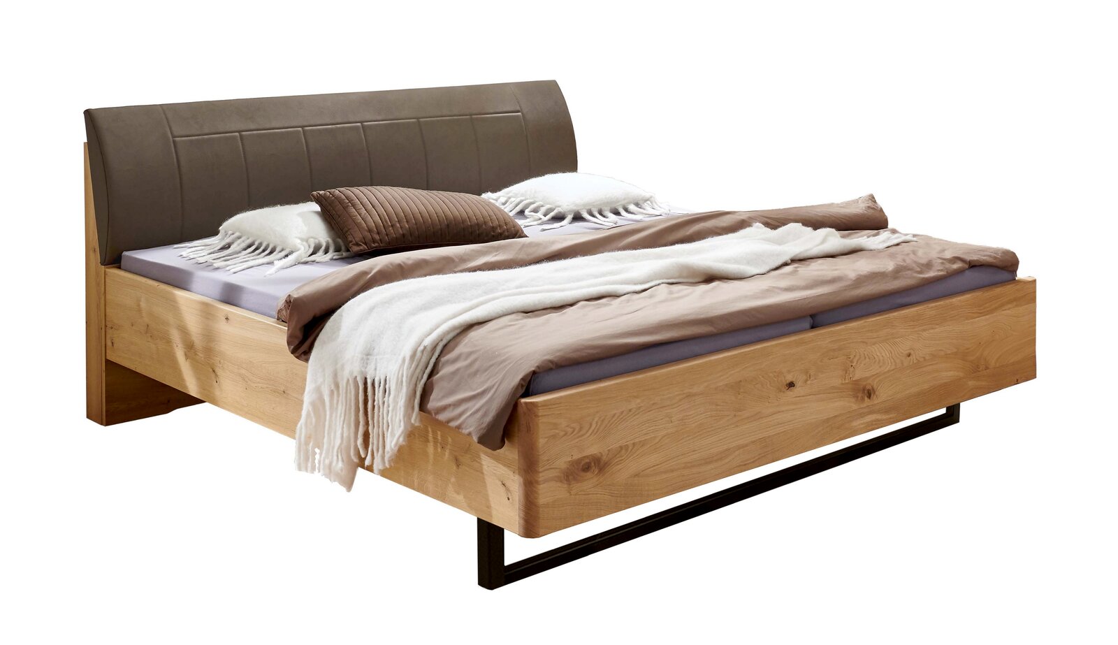 Modernes Doppelbett aus hellem Massivholz mit gepolstertem graubraunem Kopfteil, bezogen mit Bettwäsche und Decken, freigestellt auf weißem Hintergrund, Perspektive: schräg von vorne rechts.