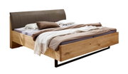 Modernes Doppelbett aus hellem Massivholz mit gepolstertem graubraunem Kopfteil, bezogen mit Bettwäsche und Decken, freigestellt auf weißem Hintergrund, Perspektive: schräg von vorne rechts.