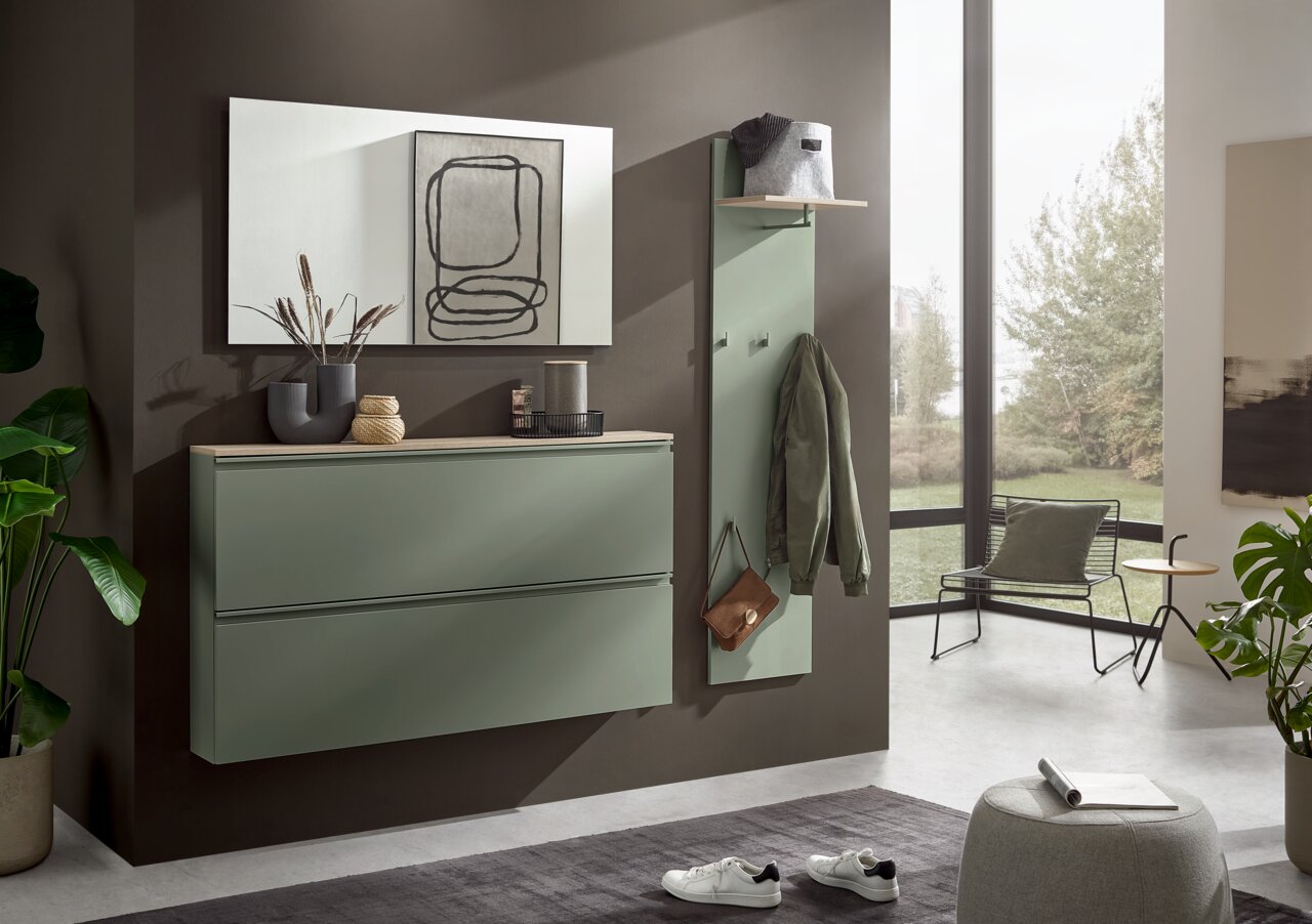 Moderne halinrichting met een aan de muur bevestigde schoenenkast in saliegroen en een kapstokpaneel met legplank en haken, zijaanzicht in een lichte hal