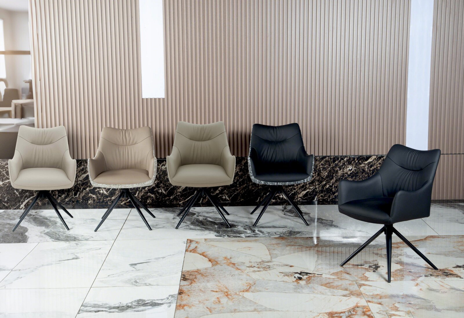 Vijf moderne fauteuils in verschillende kleuren, gezien vanaf de voorkant, op een marmeren vloer voor een geribbelde muur.