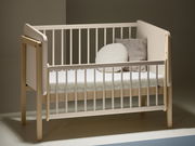 Anstellbett aus Holz mit weißem Gitter, seitliche Perspektive, zwei Kissen auf der Matratze.