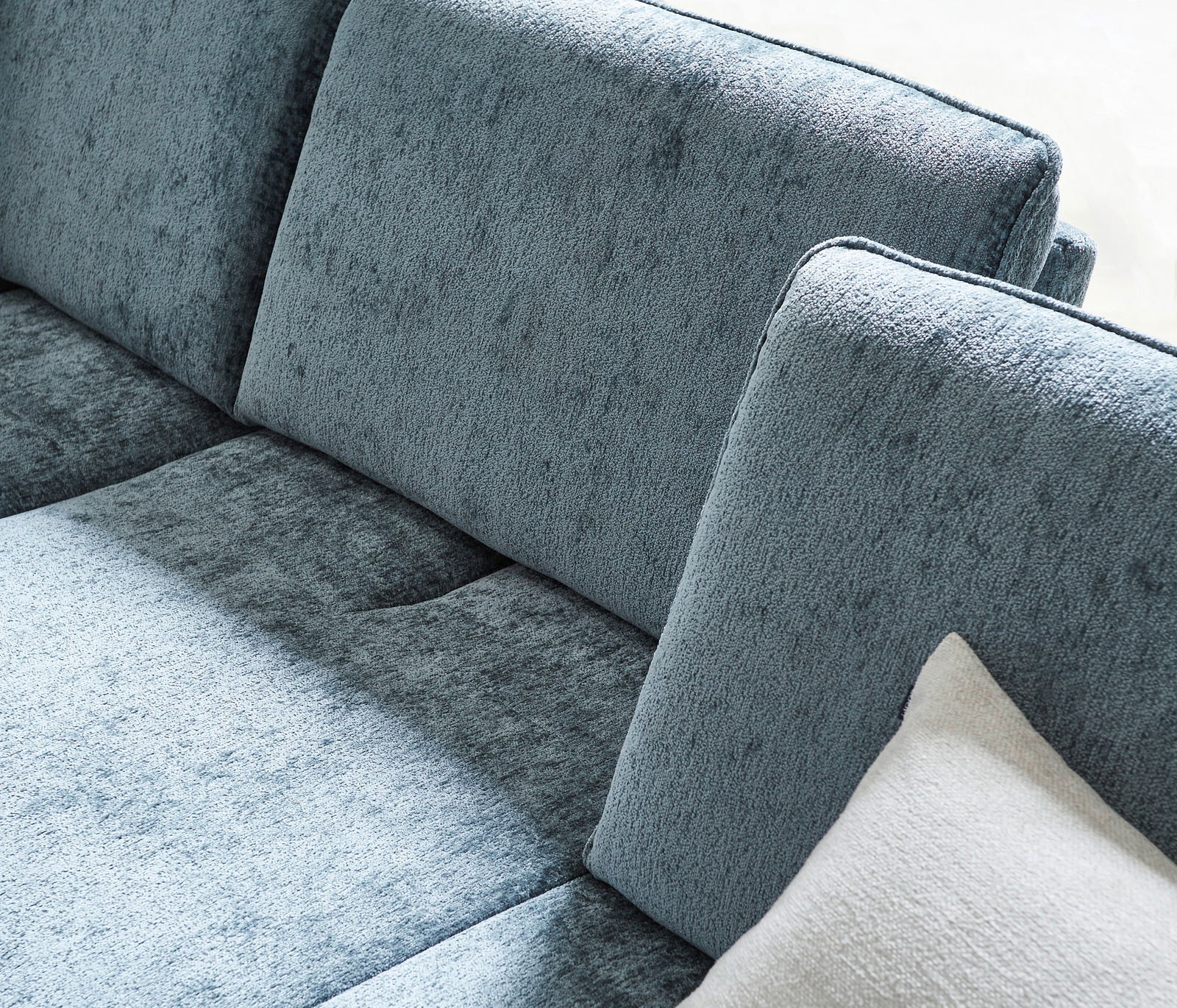 Nahaufnahme einer blauen Longchairkombination mit weicher Textur und einem weißen Kissen, seitliche Perspektive.