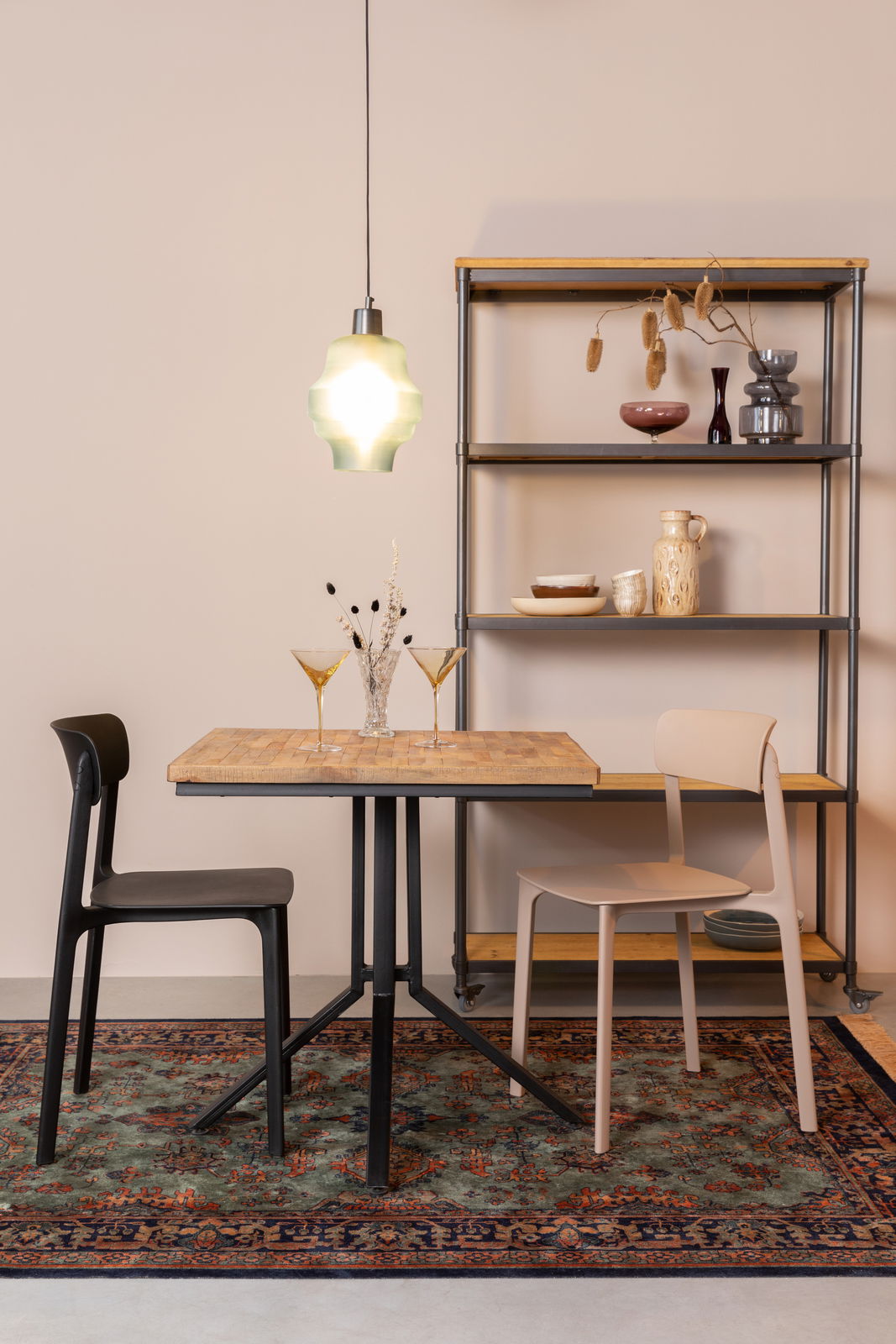 Zwei moderne Stühle in Schwarz und Beige an einem Holztisch, mit einer Hängelampe und einem Regal im Hintergrund, aus seitlicher Perspektive.