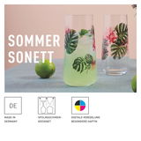 Zwei Longdrinkbecher mit tropischem Blatt- und Blumenmuster, gefüllt mit einem Getränk, auf einem Tisch mit Limetten. Vorderansicht.
