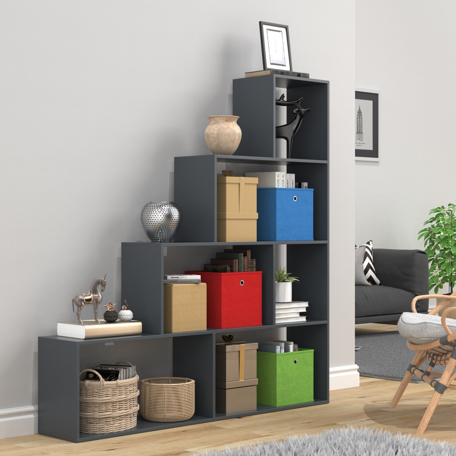 Modernes, treppenförmiges Regal in Anthrazit mit offenen Fächern und bunten Aufbewahrungsboxen, dekoriert mit Vasen, Figuren und Körben Ansicht leicht schräg von vorn im Wohnzimmer.