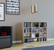 Modernes Wohnzimmer mit hellem Holzregal voller Bücher und DVDs sowie zwei zylindrischen Pendelleuchten in Gold und Silber; Perspektive: frontale Ansicht auf Augenhöhe, leicht nach rechts versetzt.