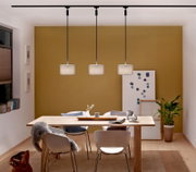 Drie moderne hanglampen in een eetkamer, gezien vanaf de voorkant, met daaronder een houten tafel en witte stoelen.