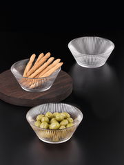 Drei Glasschalen mit geriffeltem Design, gefüllt mit Brotstangen und Oliven, auf schwarzem Hintergrund aus der Vogelperspektive.