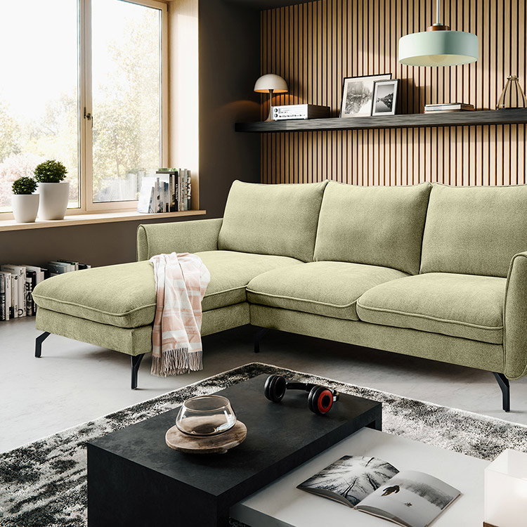 Hellgrünes Ecksofa mit Chaiselongue in einem modern eingerichteten Wohnzimmer.