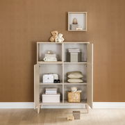 Highboard mit offenen und geschlossenen Fächern, gefüllt mit Spielzeug und Textilien, aus frontaler Perspektive.