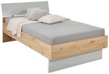 Modernes Einzelbett aus Holz mit grauem Kopfteil, grauer Bettwäsche und dekorativen Kissen, seitliche Perspektive.