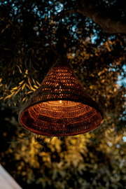 Outdoor-Hängeleuchte aus geflochtenem Material, beleuchtet in einem Baum hängend, seitliche Perspektive