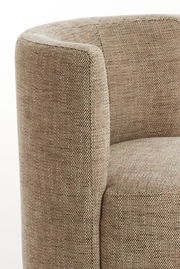 Nahaufnahme eines Sessels mit beigem Stoffbezug, seitliche Perspektive.