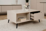 Beige Sideboard mit schwarzem Bein, offene Schublade und Bücher, aus seitlicher Perspektive fotografiert.