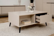Beige dressoir met zwarte poot, open lade en boeken, gefotografeerd vanuit een zijaanzicht.