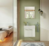 Modernes Gästebad mit weißem Waschbeckenunterschrank, grün gestrichener Wand und beleuchtetem Spiegel, seitliche Perspektive.