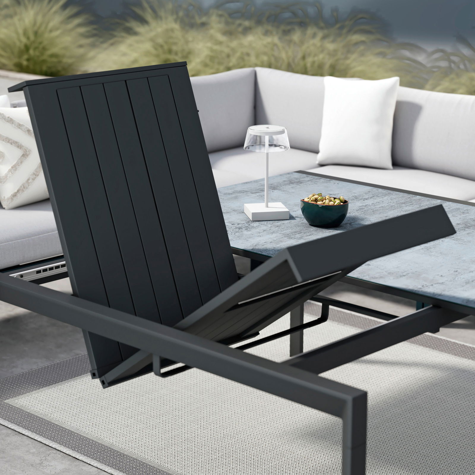 Moderner Gartentisch mit verstellbarer Tischplatte, umgeben von einem stilvollen Ecksofa, aus der Perspektive von schräg oben fotografiert.