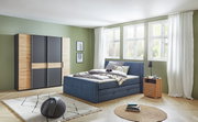 Moderne draai- en schuifdeurkast met vier deuren in houtlook en donkere accenten, aan de voorkant in de slaapkamer geplaatst.