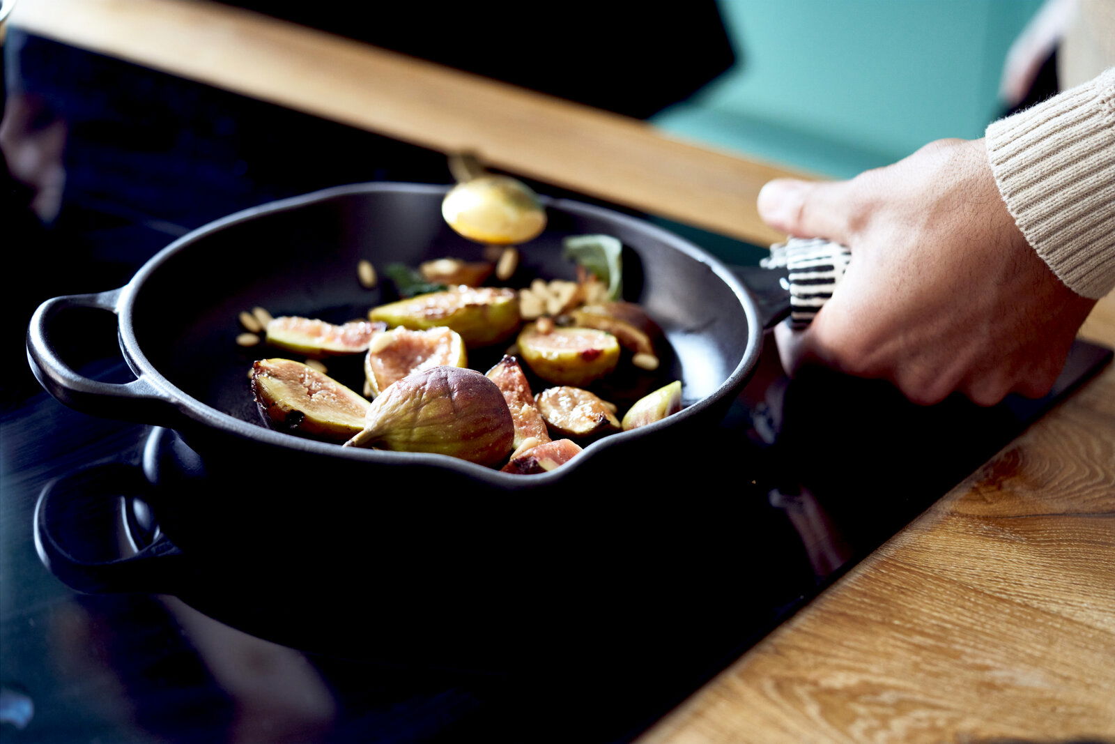 Nahaufnahme einer Brat- und Servierpfanne mit Griffen, in der auf einem Herd frische Feigen zubereitet werden.