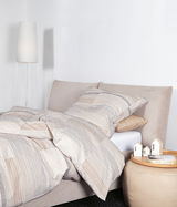 Bett mit Mako-Satin-Bettwäsche in Streifenmuster, seitliche Perspektive, mit Nachttisch und Lampe