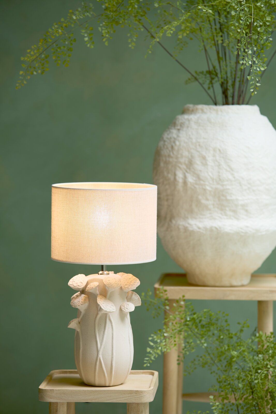 Cilindrische lampenkap in beige op een decoratieve voet met bloemmotieven, zijaanzicht
