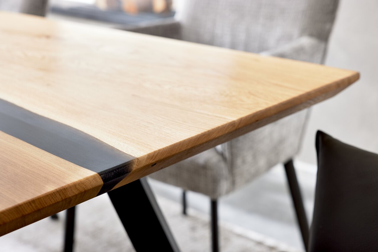 Nahaufnahme eines Esstisches aus Holz mit schwarzem Streifen, seitliche Perspektive