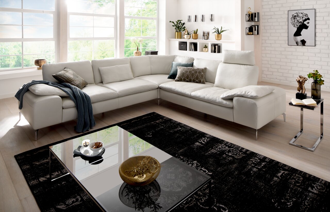 Moderne Polsterrundecke in hellem Wohnzimmer mit großen Fenstern, aus der Perspektive von vorne links fotografiert.