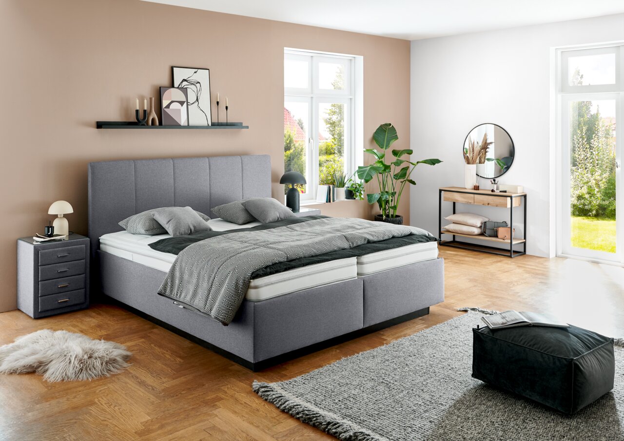 Modern gestoffeerd bed in een stijlvol ingerichte slaapkamer, zijaanzicht.