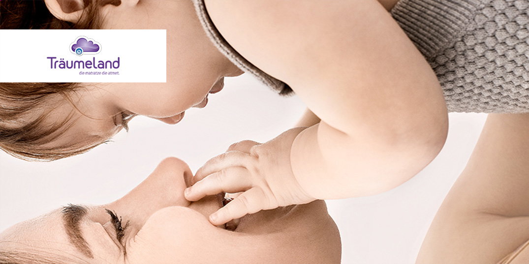 Moeder en baby kijken elkaar aan en spelen met elkaar. Logo Träumeland