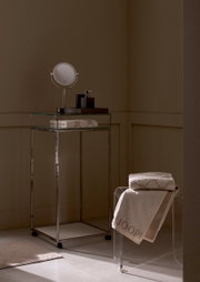 Luxuriöses Handtuch in einem stilvollen Badezimmer, auf einem transparenten Stuhl drapiert, mit elegantem Design und der Aufschrift 'JOOP!' in einer seitlichen Perspektive.