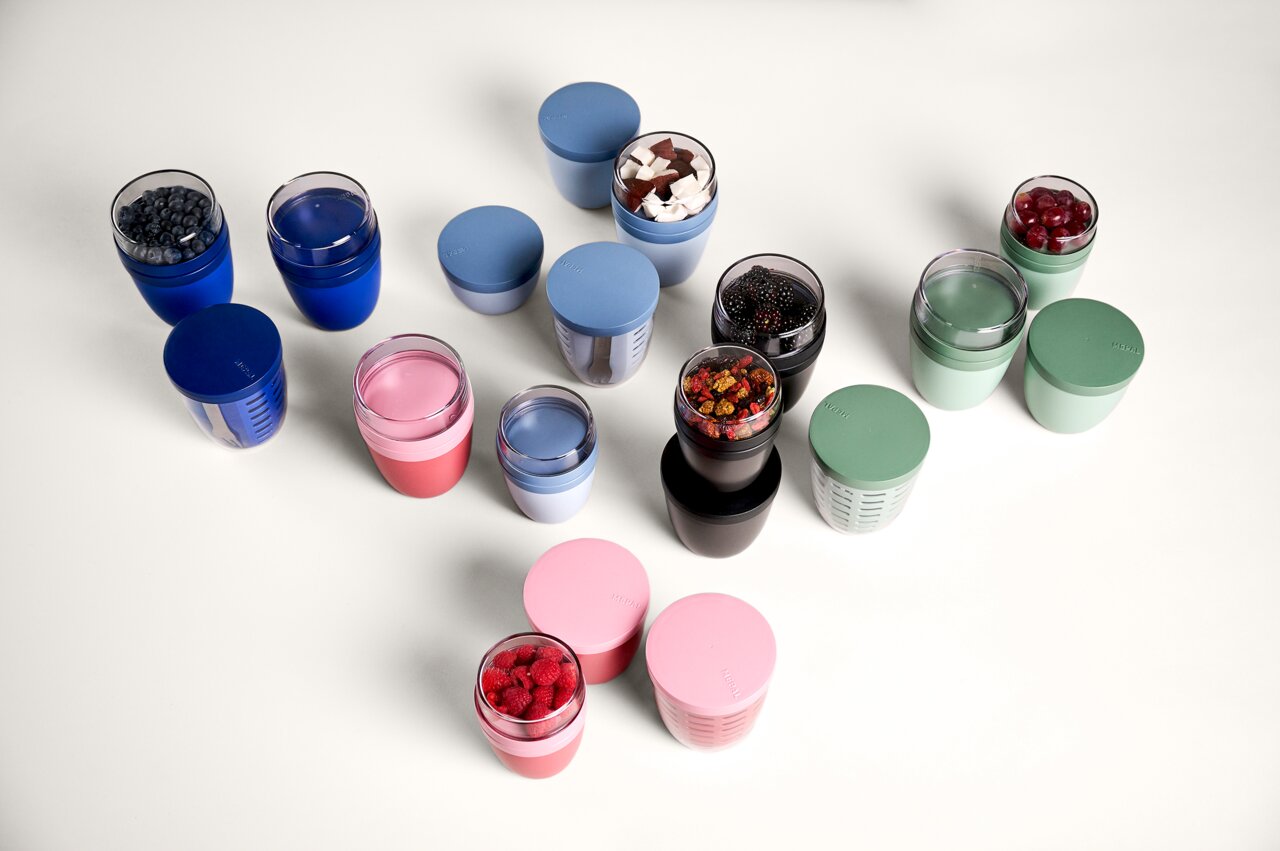 Verschiedene Snackpots in verschiedenen Farben und Größen, von oben fotografiert, gefüllt mit Beeren und anderen Snacks.