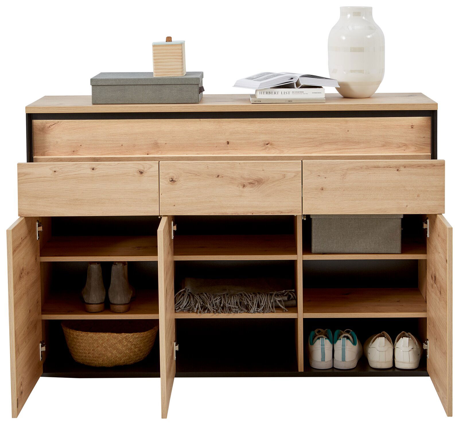 Frontale Ansicht eines modernen Sideboards mit Holzoptik, offenen Schubladen und Türen, gefüllt mit Schuhen, Körben und Dekorationen.