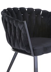 Nahaufnahme eines schwarzen Sessels mit gepolsterter Rückenlehne und Metallbeinen, seitliche Perspektive.