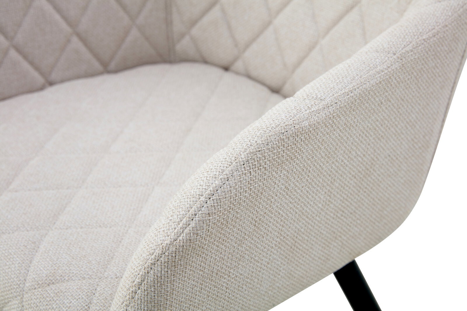 Detailaufnahme eines gepolsterten, hellbeigen Stoffstuhls mit gesteppter Sitz- und Rückenfläche, schräg von vorne rechts aufgenommen.