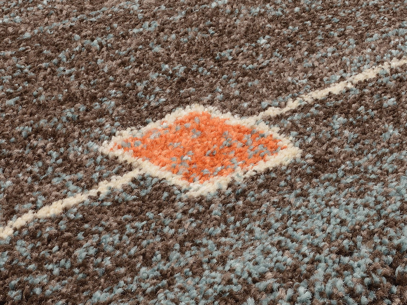 Nahaufnahme eines Frisé-Teppichs mit einem geometrischen Muster in Braun, Blau und Orange. Die Perspektive zeigt die Textur und das Design des Teppichs aus einem schrägen Winkel.