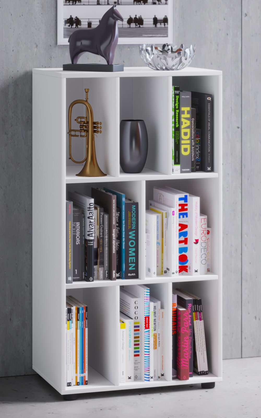 Weißes, modernes Regal mit 8 Fächern, gefüllt mit Büchern und Deko (Vase, Trompete), oben Schale und Pferdefigur; frontale leicht seitliche Perspektive.