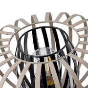 Close-up van een moderne tafellamp met een decoratief, open ontwerp van zwarte en beige spanten die een gloeilamp omringen. Aanzicht van bovenaf.