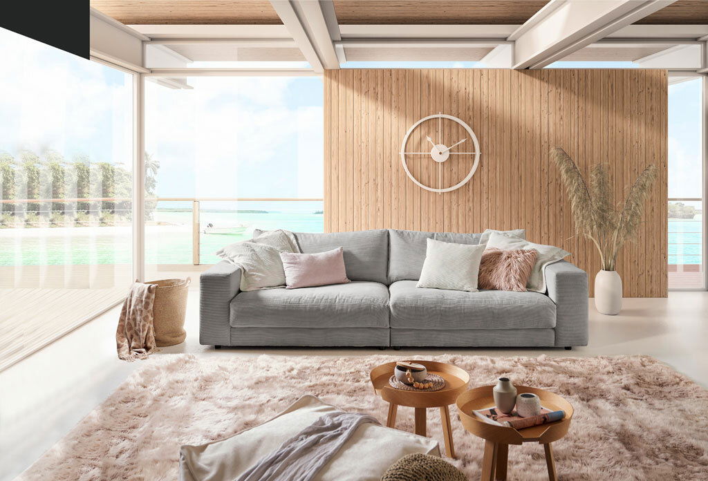 Großes, handgefertigtes Sofa in einem modernen Wohnzimmer mit Blick auf das Meer, frontal fotografiert.