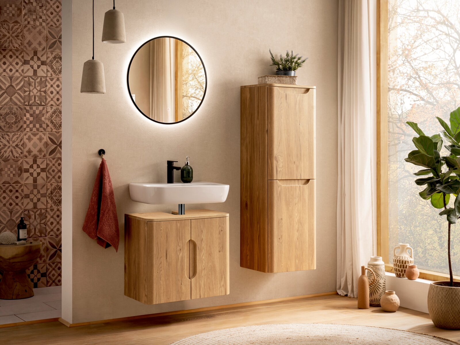 Modernes Badezimmer mit wandhängendem Waschtischunterschrank und hohem Holz-Hängeschrank, weißem Aufsatzwaschbecken, rundem beleuchtetem Spiegel und warmem Tageslicht am Fenster, frontale Perspektive