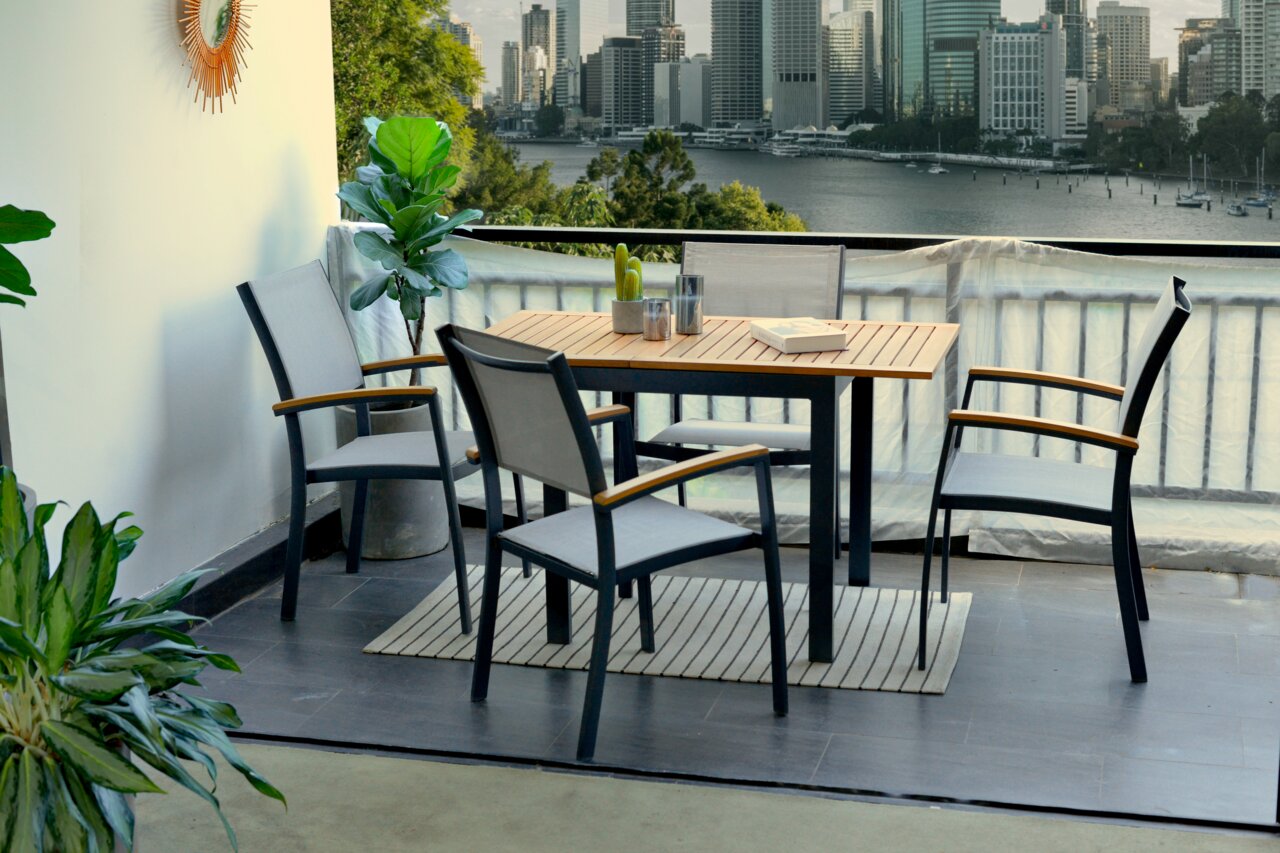 Moderner Gartentisch mit vier Stühlen auf einem Balkon mit Blick auf die Stadt. Perspektive von schräg vorne.