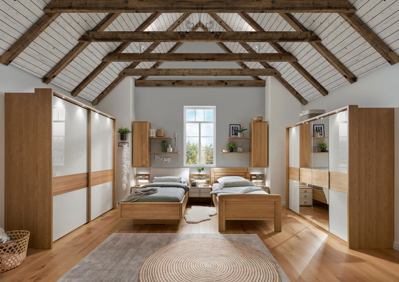 Schlafzimmer mit zwei Komfortbetten, umgeben von Schränken und Regalen in einem Raum mit Holzbalkendecke, aus zentraler Perspektive aufgenommen.