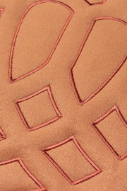 Nahaufnahme einer Zierkissenhülle mit geometrischen Stickmustern in warmen Brauntönen.