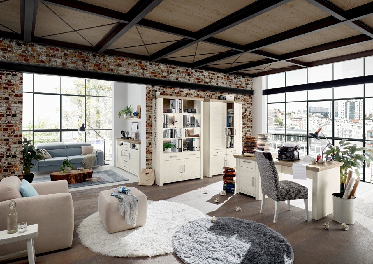 Set one by Musterring Sideboard SET ONE YORK Wohnzimmer mit modernen Möbeln in heller Holzoptik, inklusive Highboard, Vitrine und Schreibtisch, aus der Perspektive eines offenen Lofts mit Backsteinwänden und großen Fenstern.